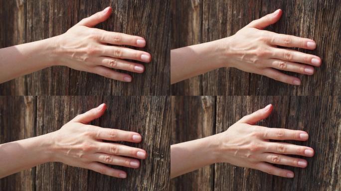 女性的手触摸坚硬粗糙的木材表面