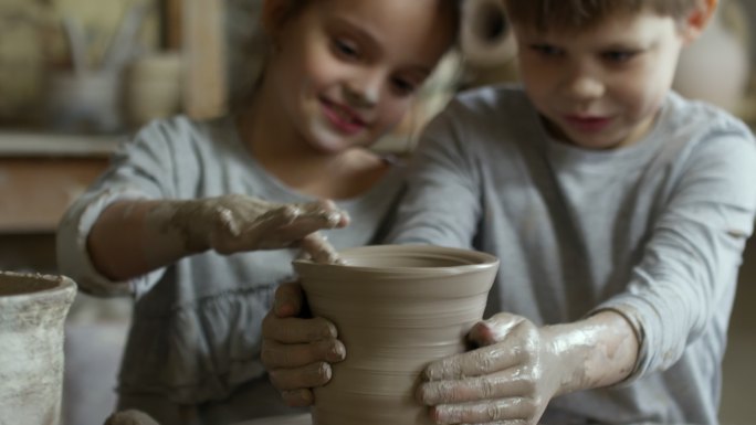 一对可爱的小学生在纺车上试着做陶器