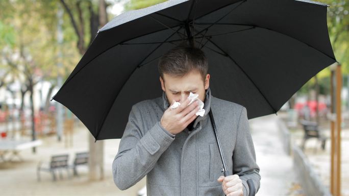 打喷嚏的男人在雨中行走