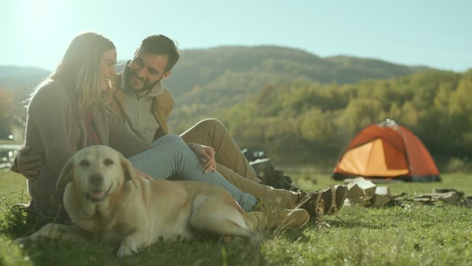 一对年轻夫妇在湖边和他们的狗玩得很开心