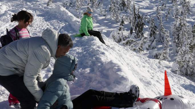 一家人乘雪橇下陡峭的雪坡，朝着树去