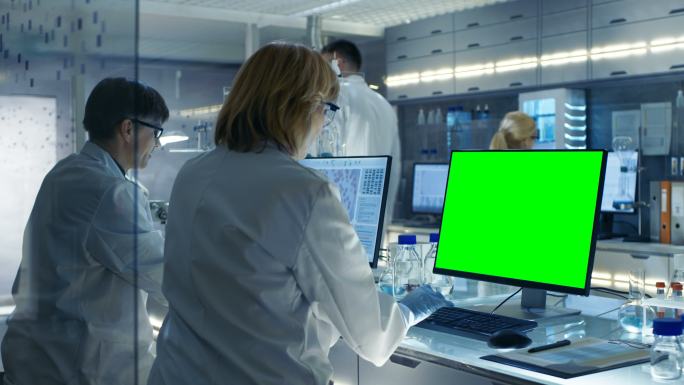 男女科学家在电脑（模拟绿色屏幕）上工作