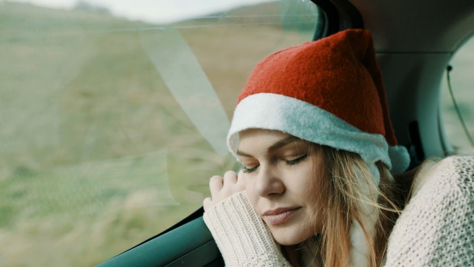头戴圣诞帽睡在汽车后座的女人