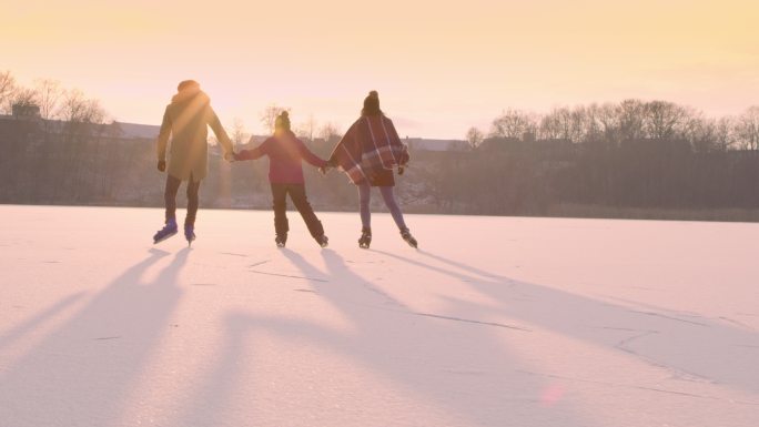 一家人手拉手在冰冻的湖面上滑冰