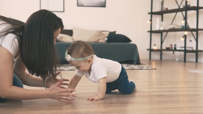 婴儿和母亲在房间里的地板上爬行