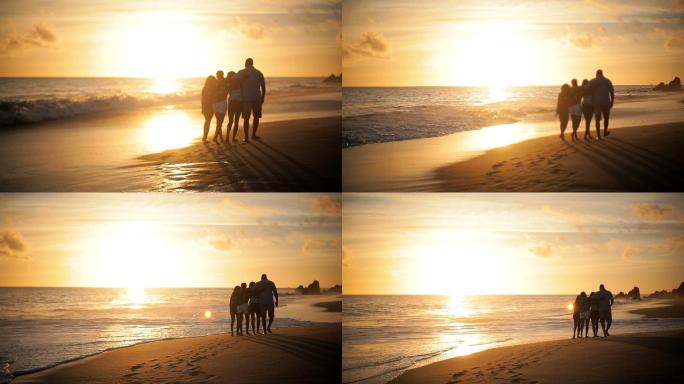 日落时一家四口在海滩上散步