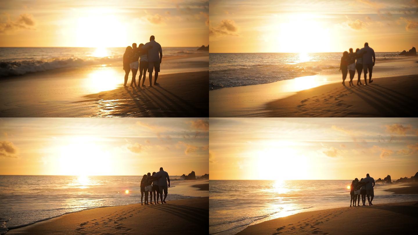 日落时一家四口在海滩上散步