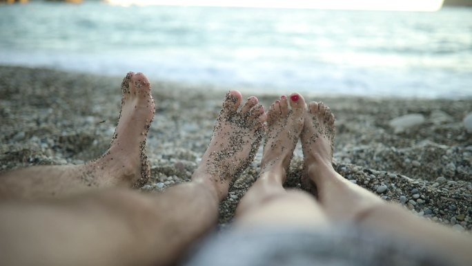 日落时躺在海滩上的脚部特写