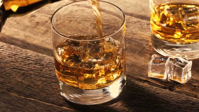 把威士忌倒进有冰块的玻璃杯里