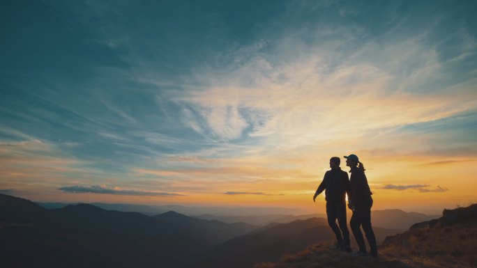 一对夫妇站在山上剪影山顶登顶