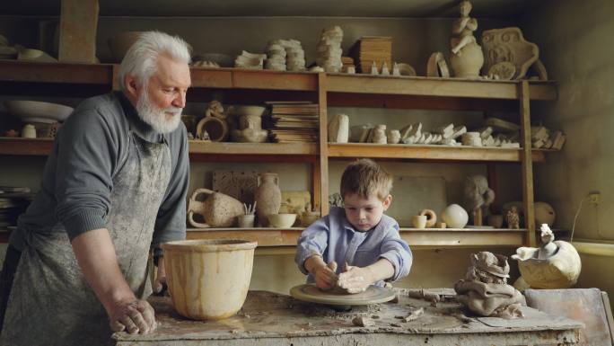 小男孩在爷爷的工作室里做泥塑