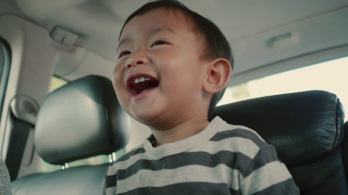 小男婴在旅途中笑着坐在汽车后座上