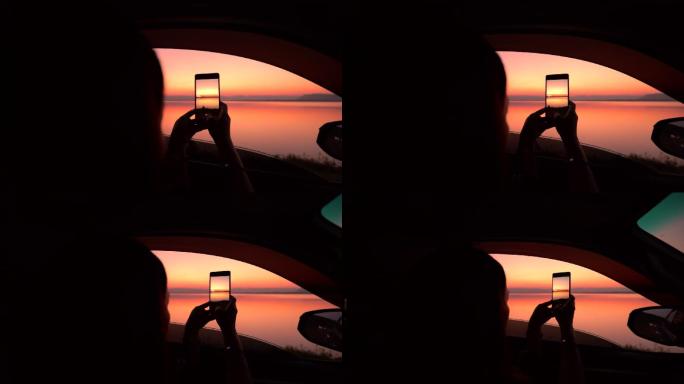 女人在车里拍摄日落的照片