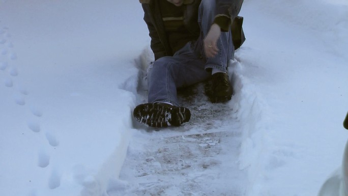 走在结冰的人行道上的年轻人滑倒了