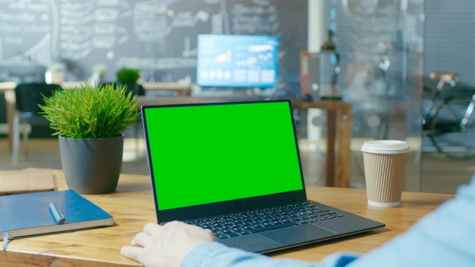 一名上班族在一台绿屏的笔记本电脑工作