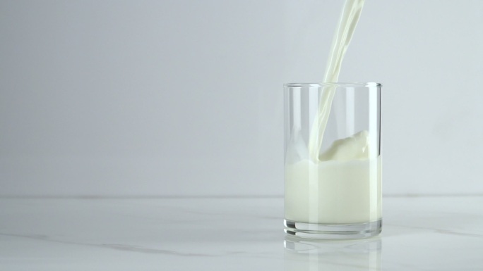 把牛奶倒进白底的杯子里。