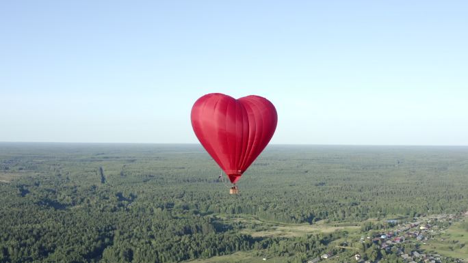 心形气球飞过绿野和森林的天际