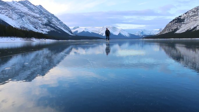 年轻人独自在美丽的山湖上滑冰
