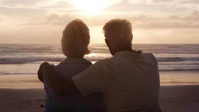 海滩上的老年夫妇观看日落的后视图