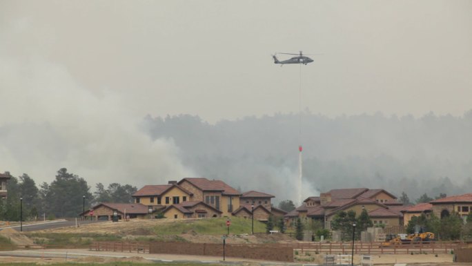一架直升机在起火的房屋上空扑火