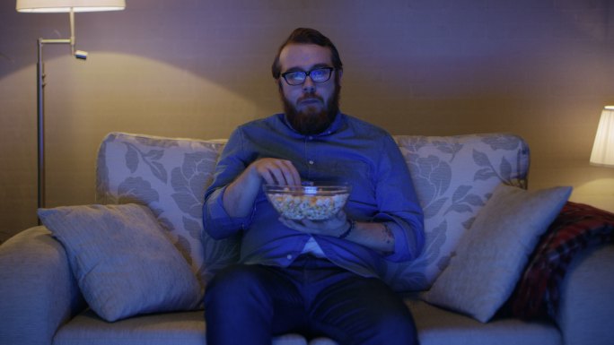 一个男人坐在沙发上吃爆米花