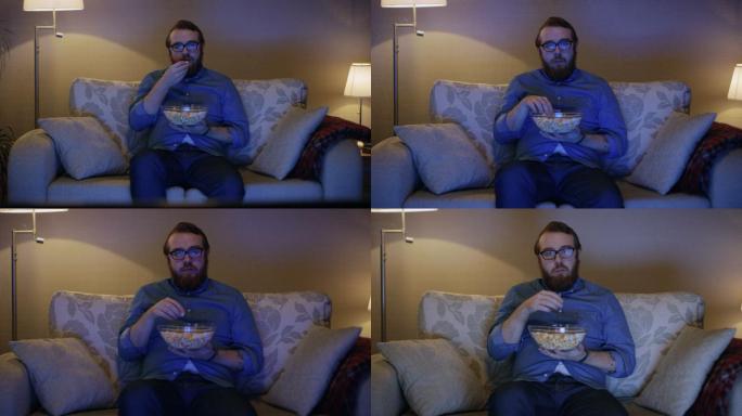一个男人坐在沙发上吃爆米花