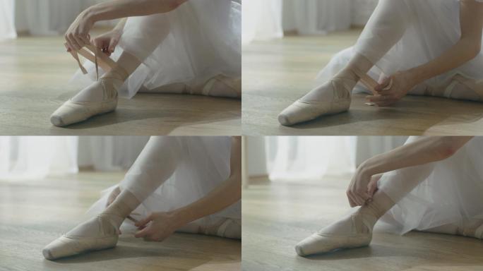 芭蕾舞演员坐在木地板上系鞋带