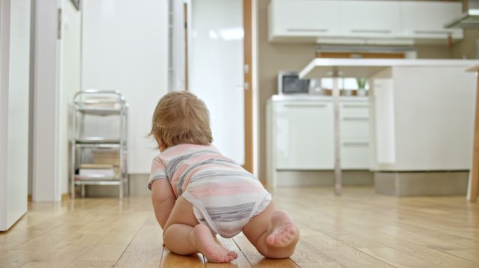 一个婴儿在木地板上爬行