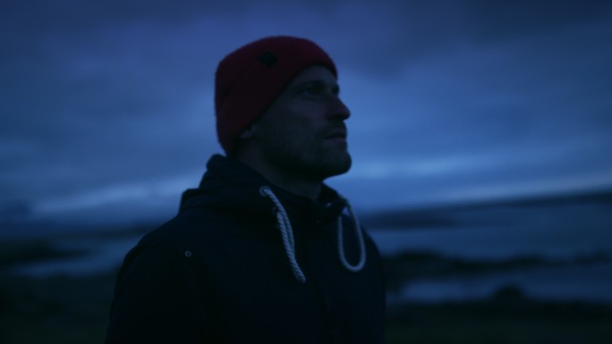 日落后凝视冰岛海岸的年轻人