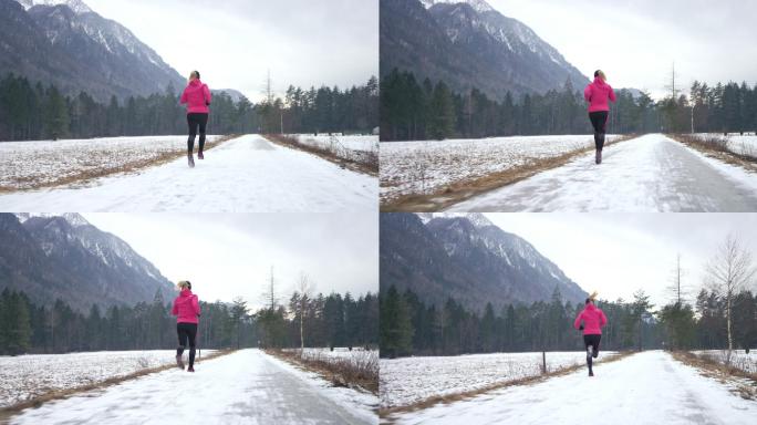 一名女跑步者在雪地上的人行道上跑步。