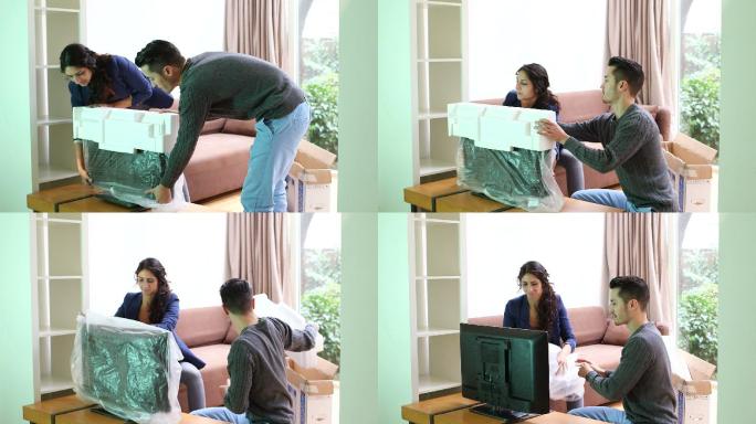 一对年轻夫妇在客厅安装新电视