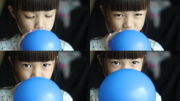给蓝色气球充气的女孩