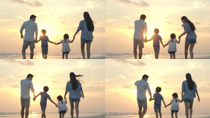 快乐的家庭在日落时分漫步在海滩上度假旅游