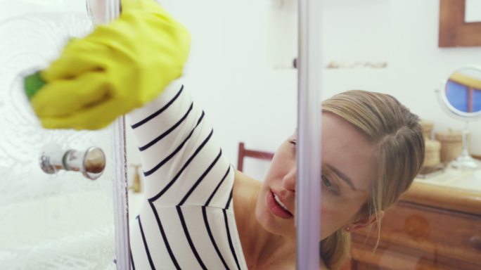 一个年轻女子在擦洗淋浴间的玻璃