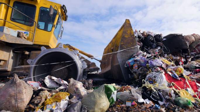 一辆垃圾掩埋车将一堆大垃圾运走的低视图。