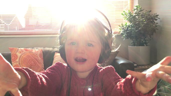 小女孩带着耳机在家听音乐