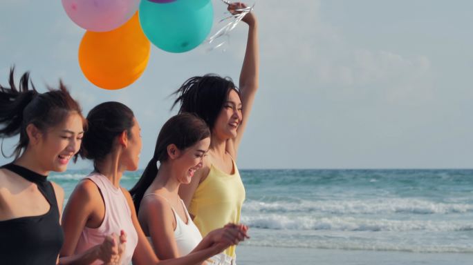朋友们拿着气球在沙滩上奔跑