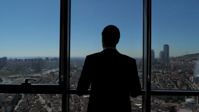 一个男人正从他的公寓里眺望城市全景。