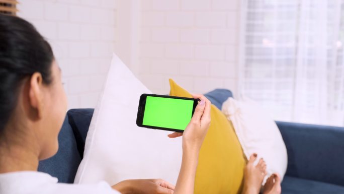 女人躺在沙发上看绿屏手机视频