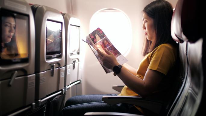 女乘客在飞机上读杂志和放松