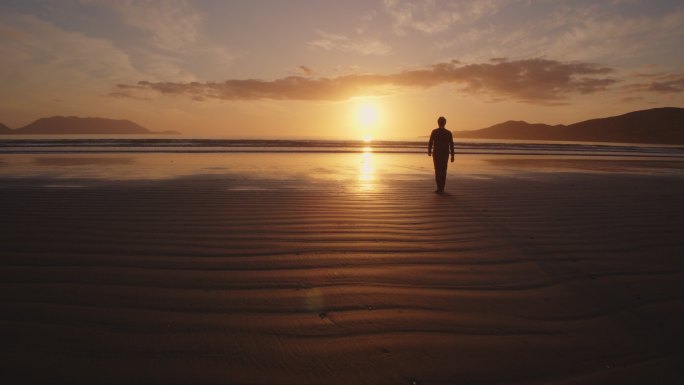 男子在海边沙滩上行走的剪影