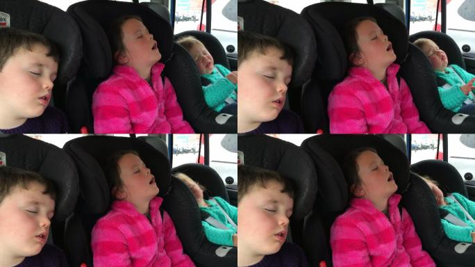 长途旅行后睡在车后座的孩子们