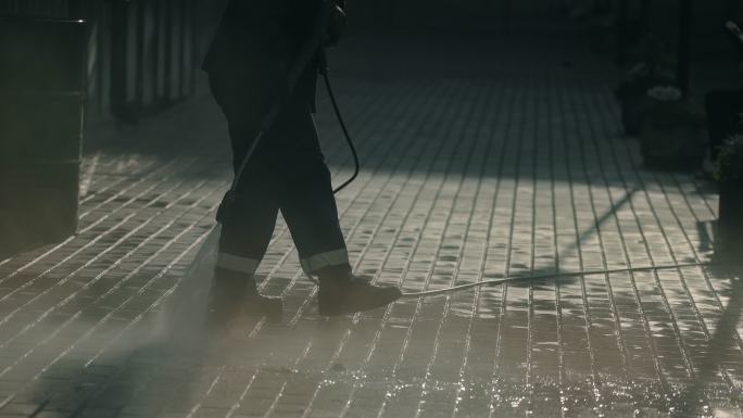 城市工人用强力喷射水清洁人行道砖块