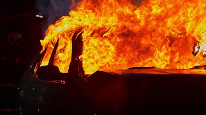 一辆撞毁的汽车在夜间被大火烧毁