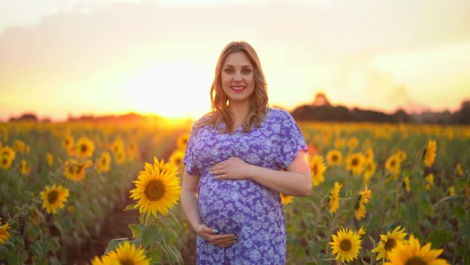 一位怀孕的年轻妇女在向日葵地里享受