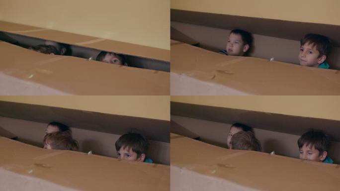 三个男孩在纸板箱里偷看，躲在纸箱里