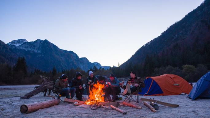 一群朋友野营，坐在营火旁