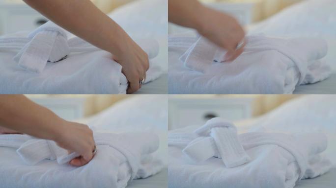 一个女人把干净的浴衣放在酒店的床上