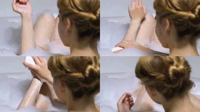 美丽的女士在沐浴时使用保湿有机皂