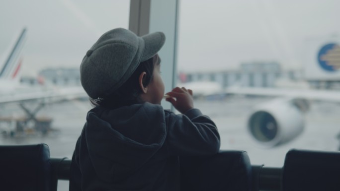 一个小男孩在机场看飞机。